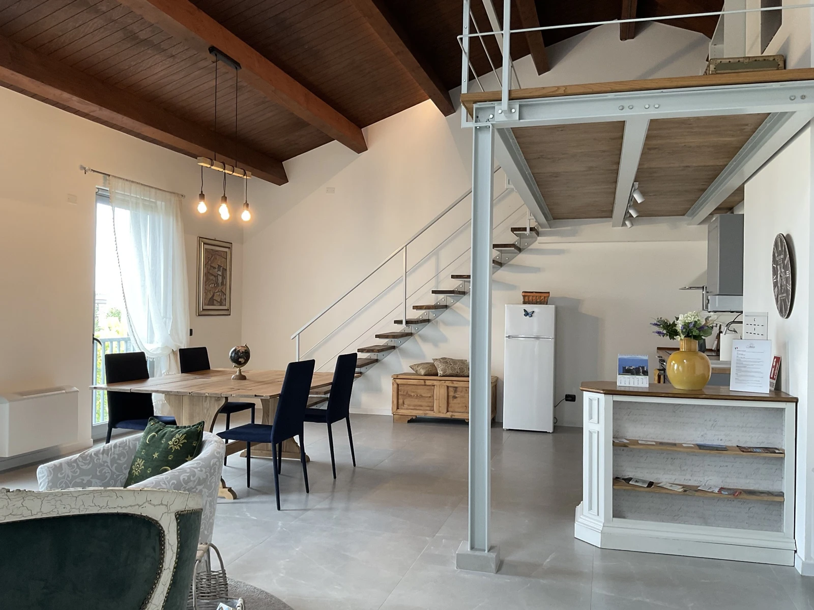 Wide view of the shared living area, with dining table, kitchen and stairs
